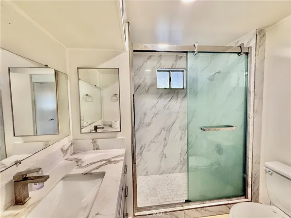 a bathroom with a granite countertop shower sink vanity and mirror