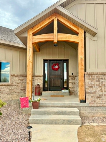 2101 Goose Ranch Road Vernal, UT 84078 - Photo 3 of 72 Inviting covered entry featuring a prominent timber frame, a dark wood-paneled door with sidelights, and board and batten siding