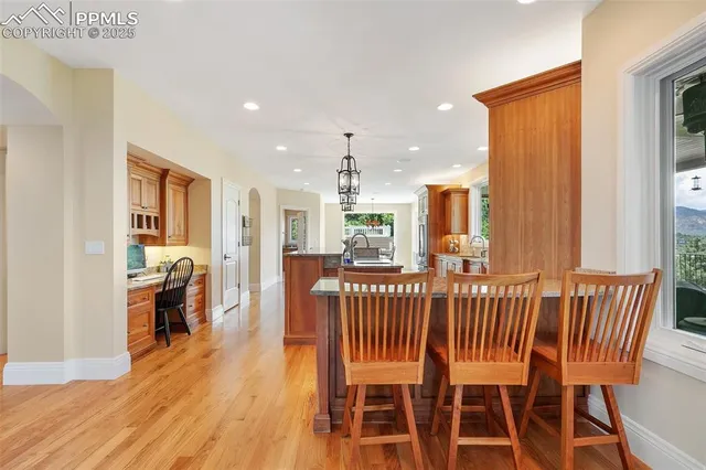 a kitchen with stainless steel appliances granite countertop a refrigerator a sink dishwasher a stove and a dining table with wooden floor