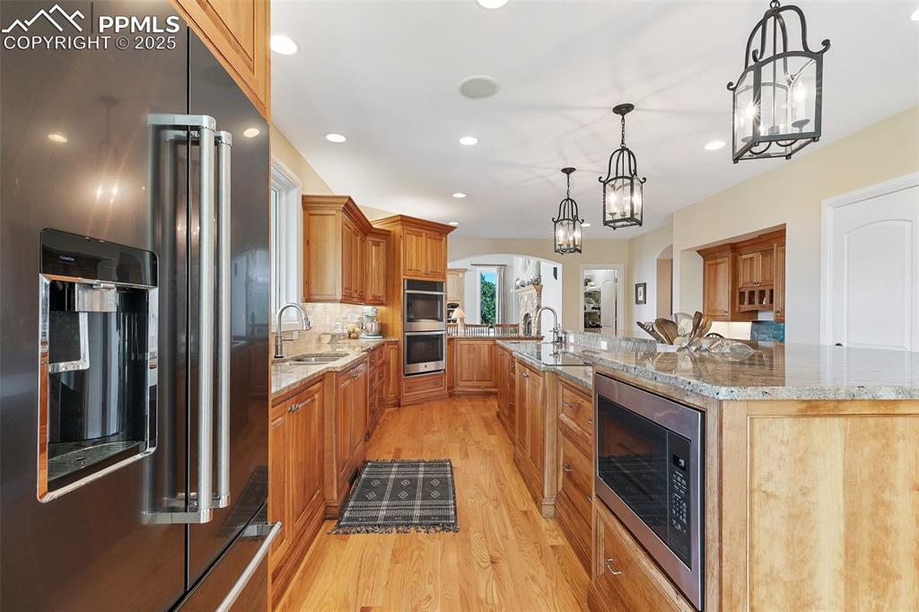 4490 Star Ranch Road Colorado Springs, CO 80906 - Photo 15 of 50 a kitchen with stainless steel appliances granite countertop a refrigerator a sink dishwasher a stove and a dining table with wooden floor