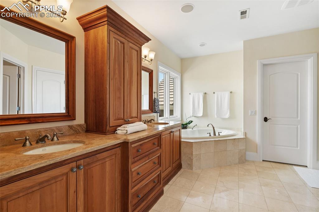 4490 Star Ranch Road Colorado Springs, CO 80906 - Photo 23 of 50 a spacious bathroom with a double vanity sink a mirror and a bathtub