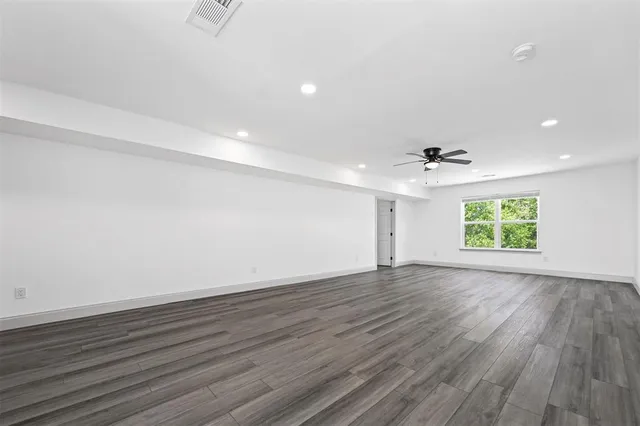 an empty room with wooden floor chandelier and windows