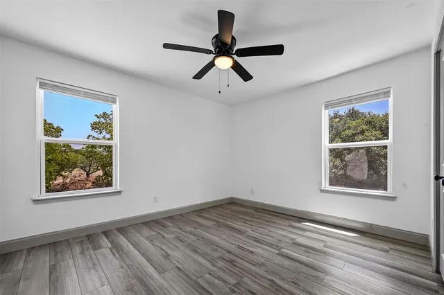 a view of empty room with wooden floor and ceiling fan