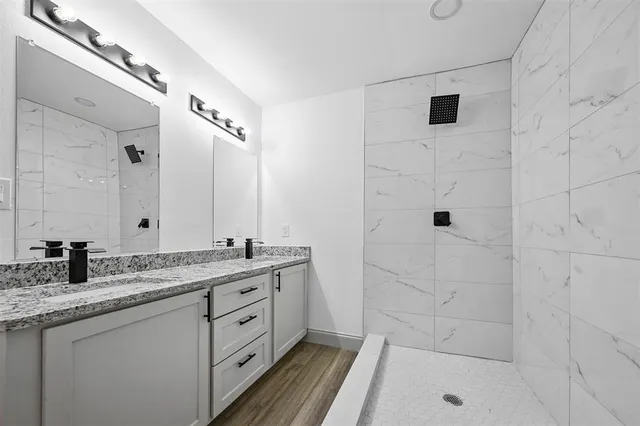 a bathroom with a granite countertop sink a mirror and shower