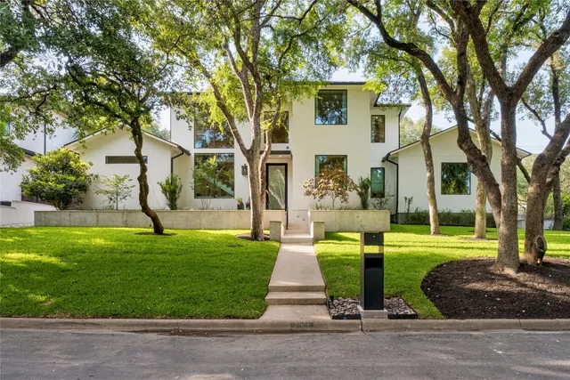 a front view of a house with garden and trees