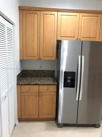 an empty room with wooden floor cabinet and windows