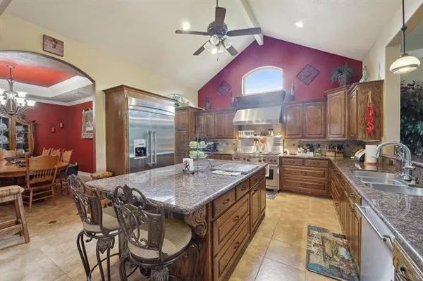 a kitchen with stainless steel appliances granite countertop a stove top oven a sink a dining table and chairs with wooden floor