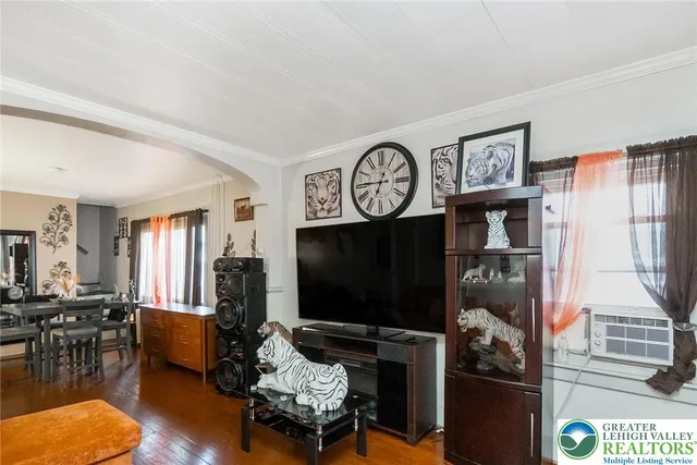 a living room with furniture a flat screen tv and floor to ceiling window