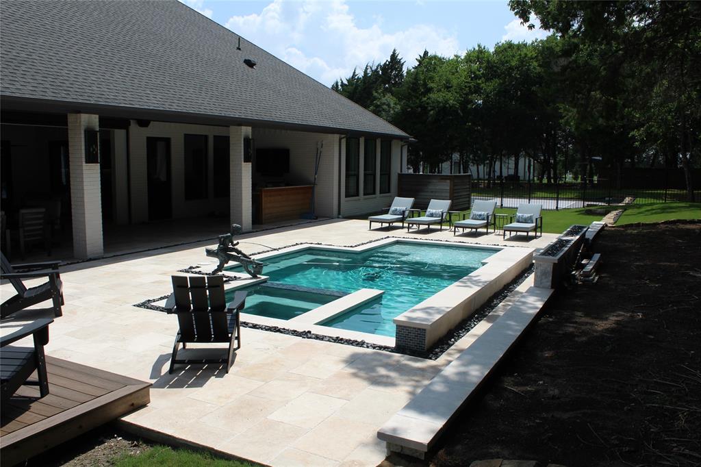 333 Renaissance Lane Heath, TX 75032 - Photo 8 of 35 Expansive backyard featuring a geometric pool with integrated spa, broad stone patio, and a covered patio area with built-in cabinetry
