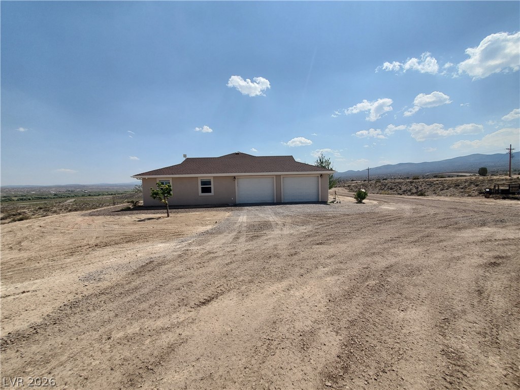 5272 Truman Lane Caliente, NV 89008 - Photo 24 of 43 View of property exterior with a garage, dirt driveway, and a mountain view