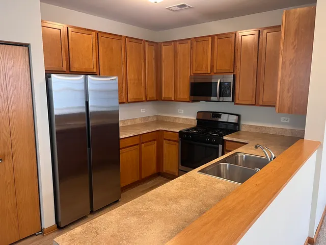 a kitchen with a refrigerator sink and cabinets