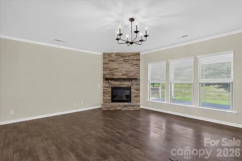 a view of an empty room with wooden floor fireplace and a window