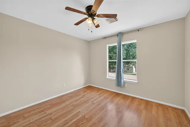an empty room with a window and a fan
