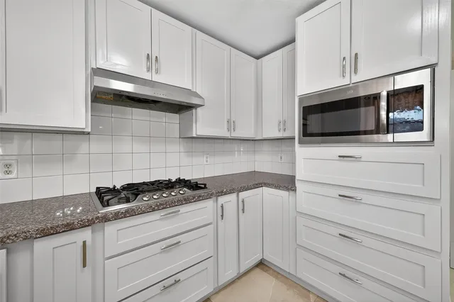 a kitchen with granite countertop white cabinets and black appliances
