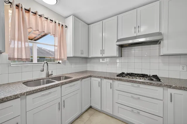 a kitchen with granite countertop a sink a window and cabinets