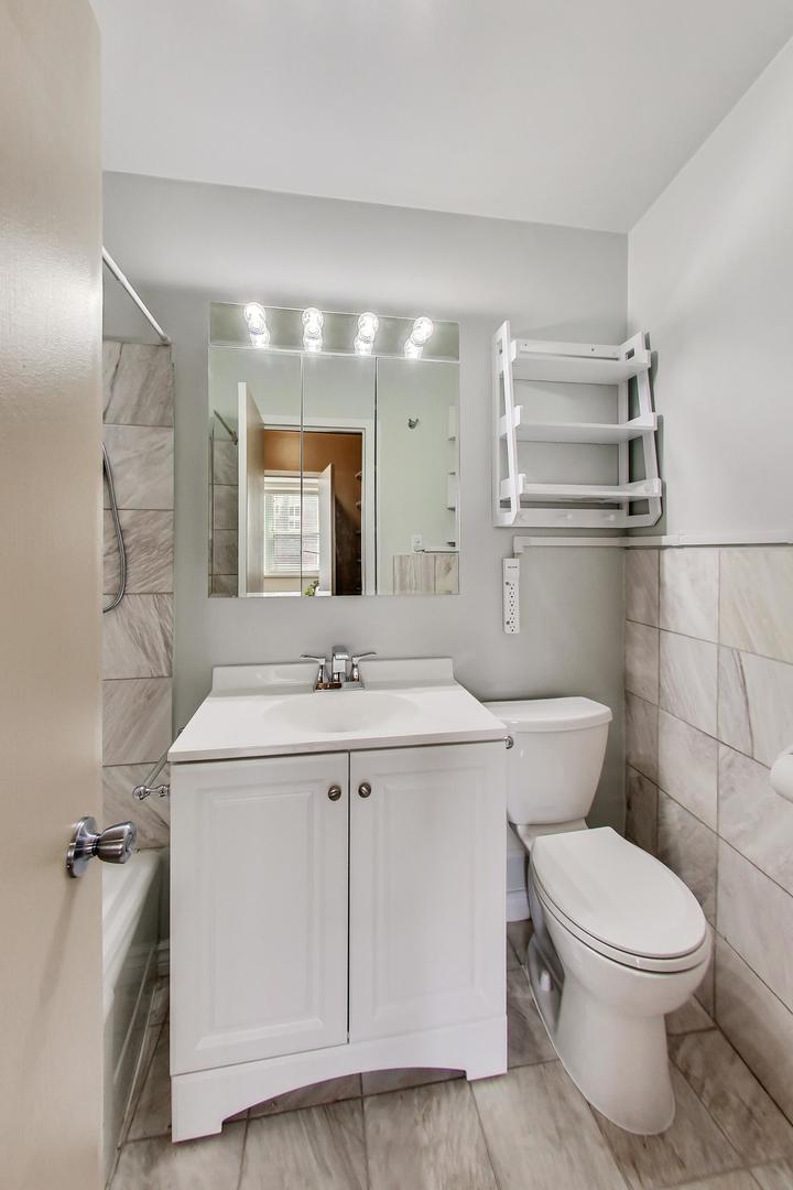 1150 North Lake Shore Drive, Unit 11J Chicago, IL 60611 - Photo 22 of 34 a bathroom with a sink a toilet a mirror and window