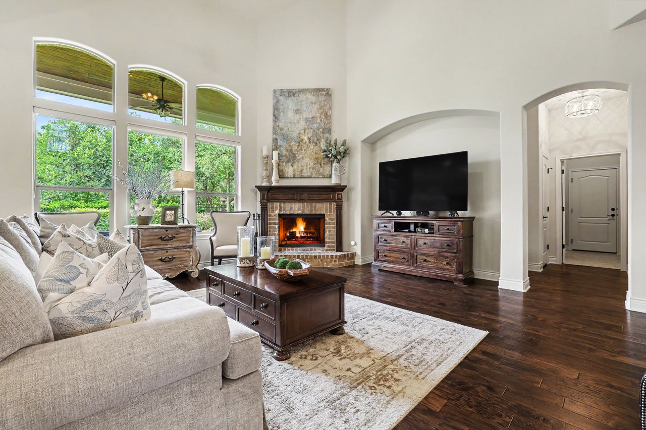 809 Prairie Dunes Drive Georgetown, TX 78628 - Photo 8 of 40 A spacious living area with soaring ceilings and a cozy brick fireplace, bathed in natural light from tall arched windows.