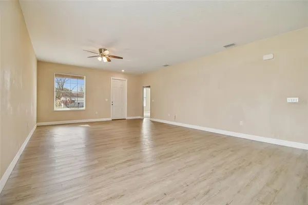 a view of an empty room with a window and wooden floor