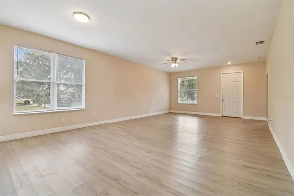 an empty room with wooden floor and windows
