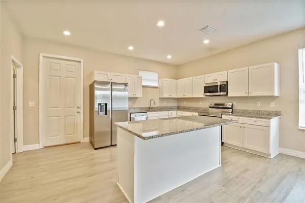 a kitchen with stainless steel appliances granite countertop a sink and a refrigerator