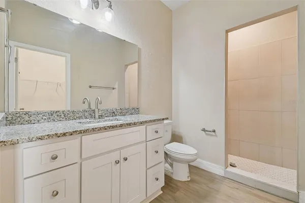 a bathroom with a granite countertop sink a toilet and a shower