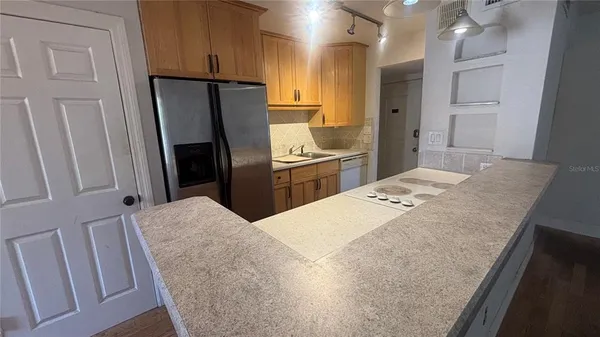 a kitchen with stainless steel appliances granite countertop a refrigerator a stove and a sink with wooden floor