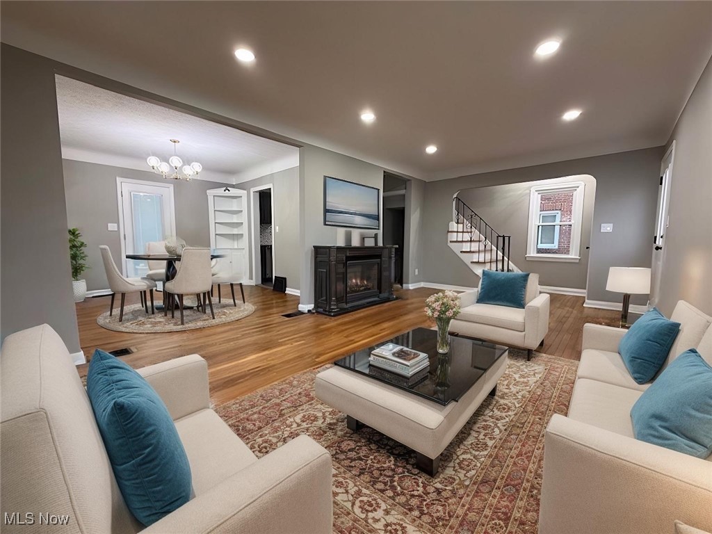 6807 Gerald Avenue Parma, OH 44129 - Photo 3 of 25 Living area with a glass covered fireplace, wood finished floors, recessed lighting, stairway, and a chandelier virtually staged