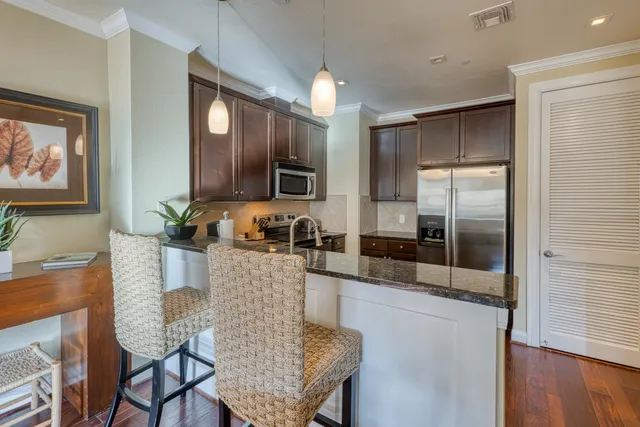 a kitchen with granite countertop a refrigerator a stove a sink dishwasher with a dining table and chair