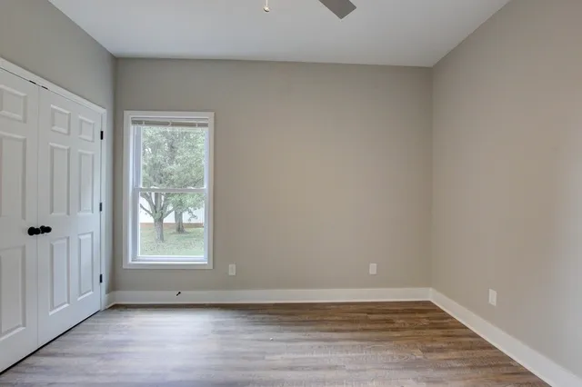 a view of an empty room with wooden floor and a window