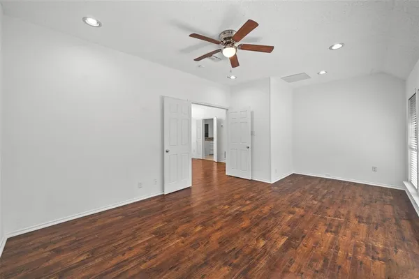 an empty room with wooden floor and a ceiling fan
