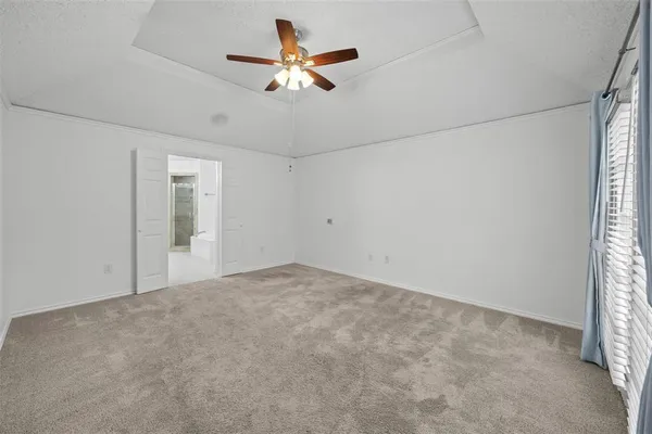 an empty room with a chandelier fan and windows