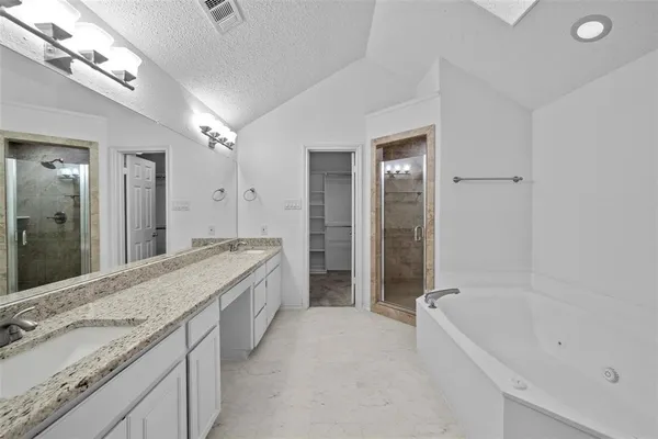 a spacious bathroom with a granite countertop tub a double vanity sink and a large mirror