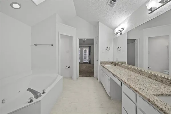 a bathroom with a granite countertop sink mirror and a bathtub