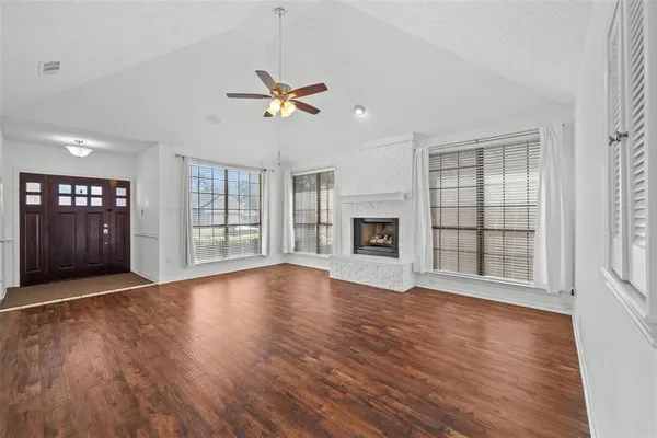 a view of an empty room with window and wooden floor