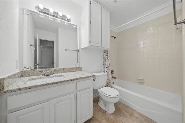 a bathroom with a granite countertop toilet a sink and a bathtub
