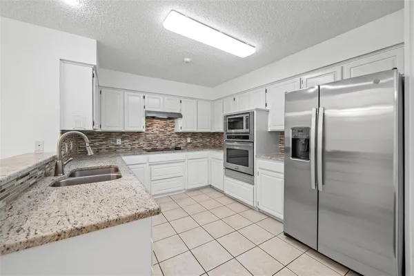 a kitchen with granite countertop a refrigerator sink and cabinets