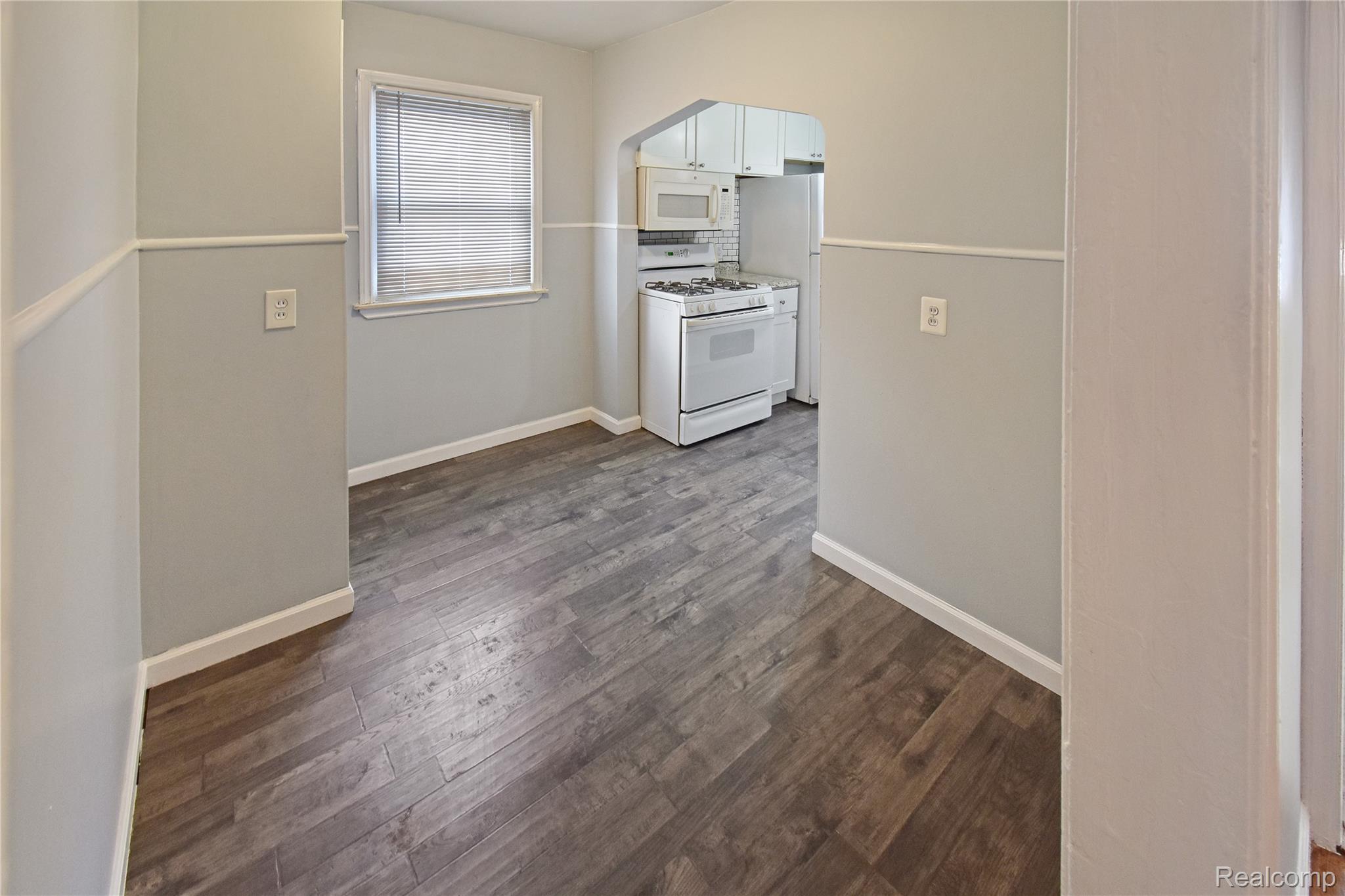 8305 Stephens Road Center Line, MI 48015 - Photo 5 of 23 Kitchen with white appliances, white cabinets, arched walkways, and dark wood-style flooring