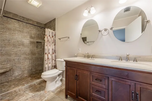 a spacious bathroom with a double vanity sink toilet and a mirror