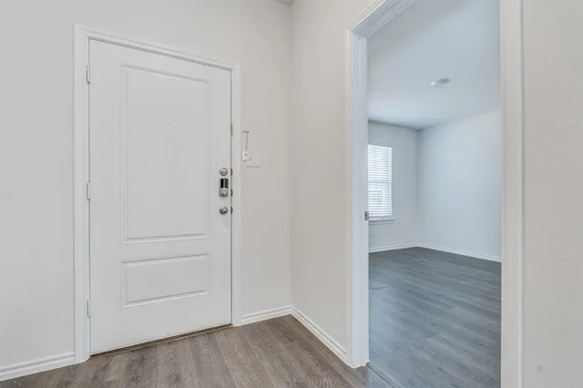a view of an empty room with closet and wooden floor