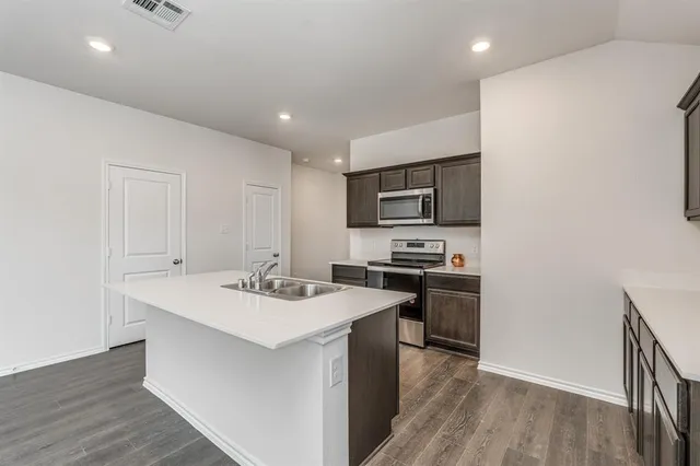 a kitchen with a sink a stove top oven and wooden floor