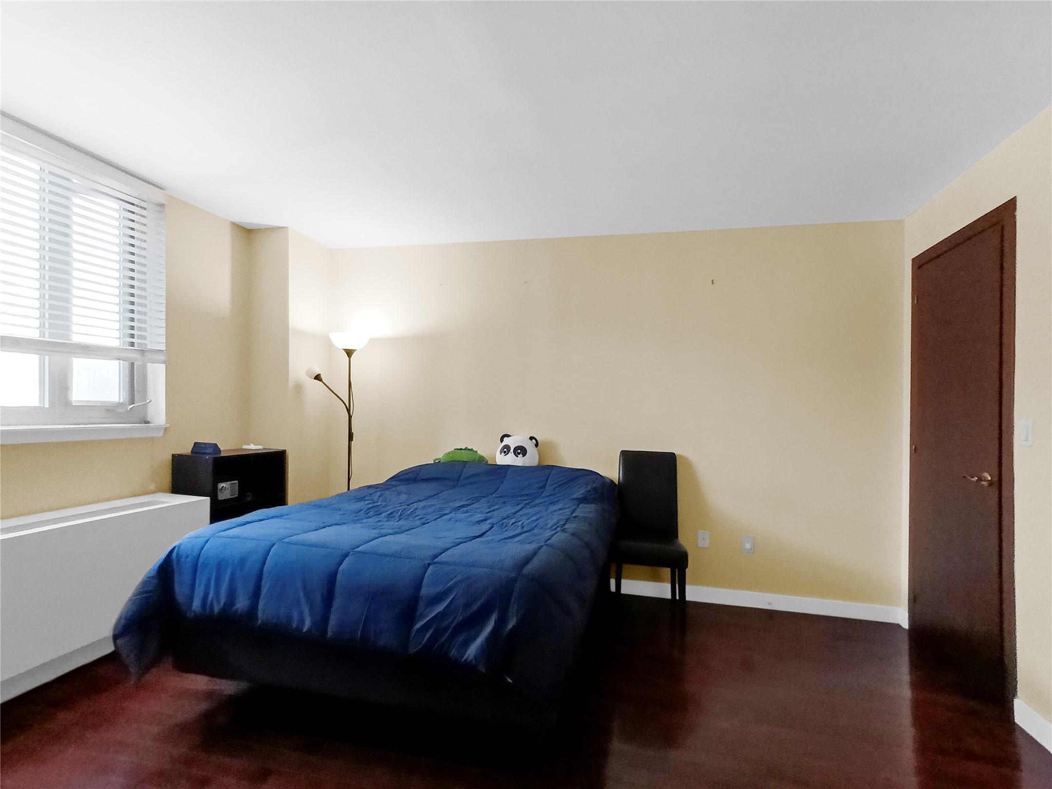 133-38 Sanford Avenue, Unit 6A Queens, NY 11355 - Photo 11 of 22 a bed sitting in a bedroom next to a window and a chair