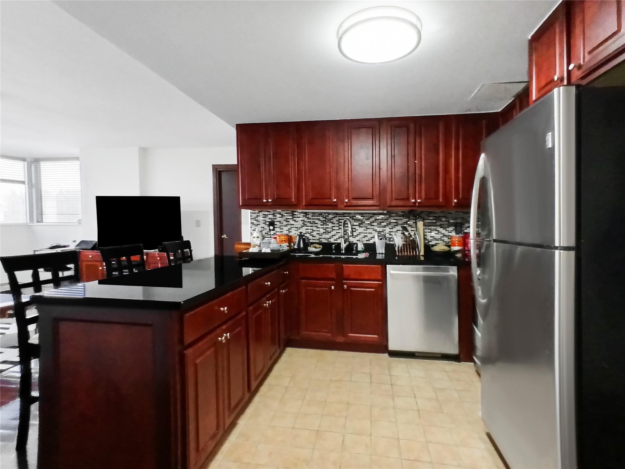 133-38 Sanford Avenue, Unit 6A Queens, NY 11355 - Photo 6 of 22 a kitchen with stainless steel appliances granite countertop a refrigerator and a stove top oven