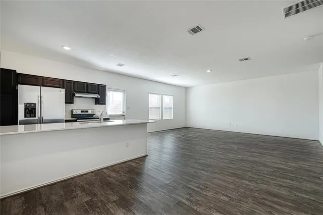 a large kitchen with stainless steel appliances a large counter top a stove and a wooden floors