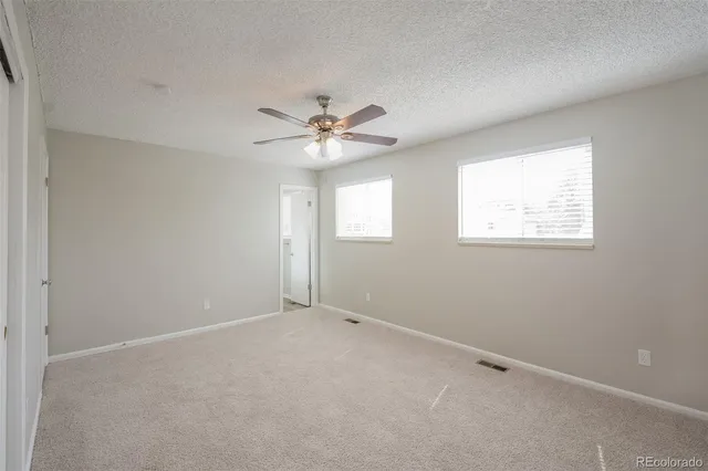an empty room with windows and fan