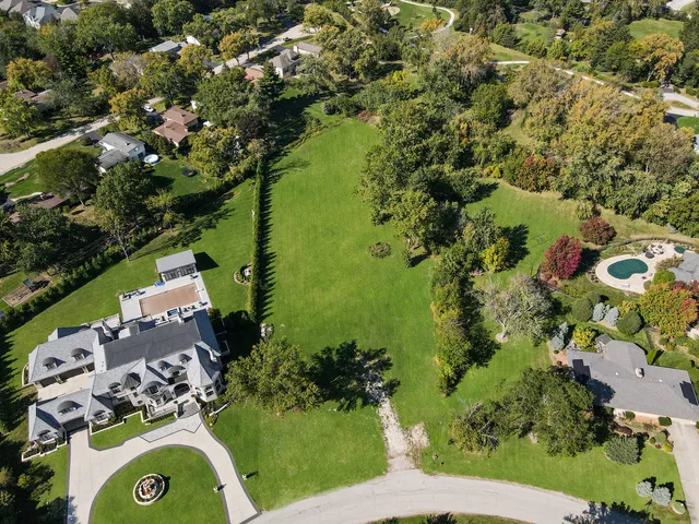 an aerial view of a residential houses with outdoor space and trees all around