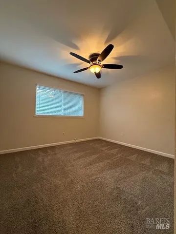 an empty room with a chandelier fan and windows