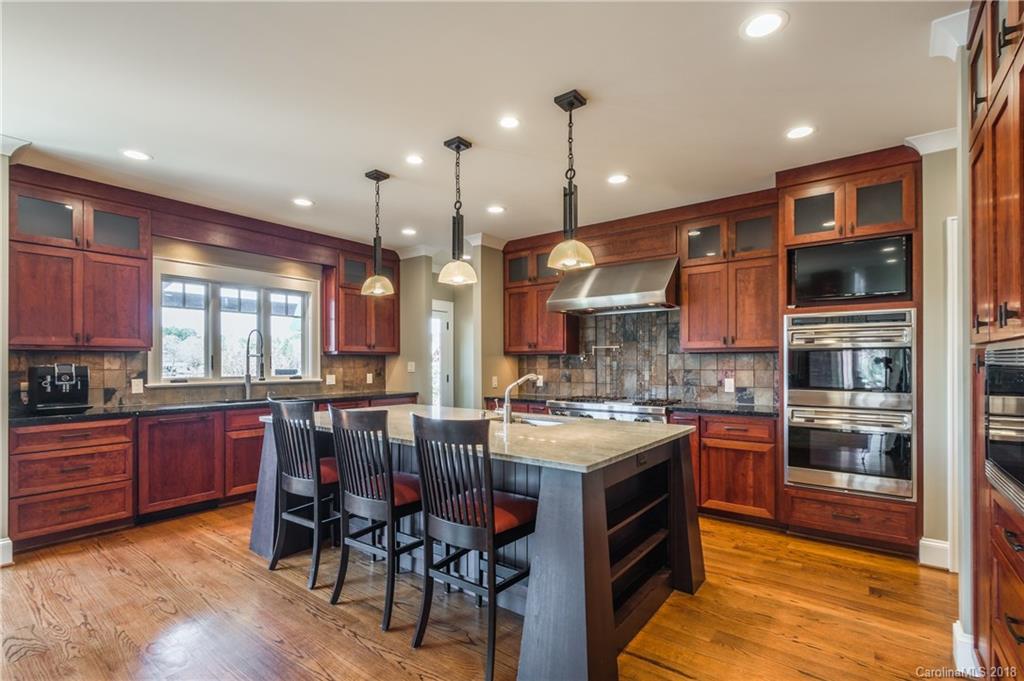 2649 River Ridge Place Fort Mill, SC 29708 - Photo 11 of 34 a kitchen with a stove a sink a kitchen island with wooden cabinets and chairs