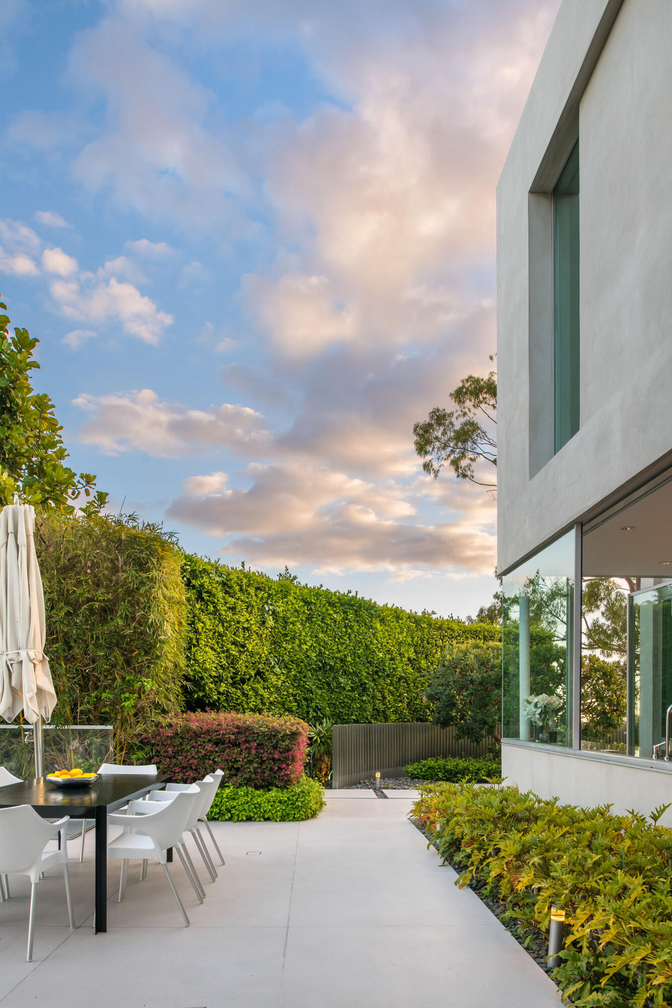 1288 Angelo Drive Beverly Hills, CA 90210 - Photo 29 of 33 a view of a patio with a table and chairs under an umbrella