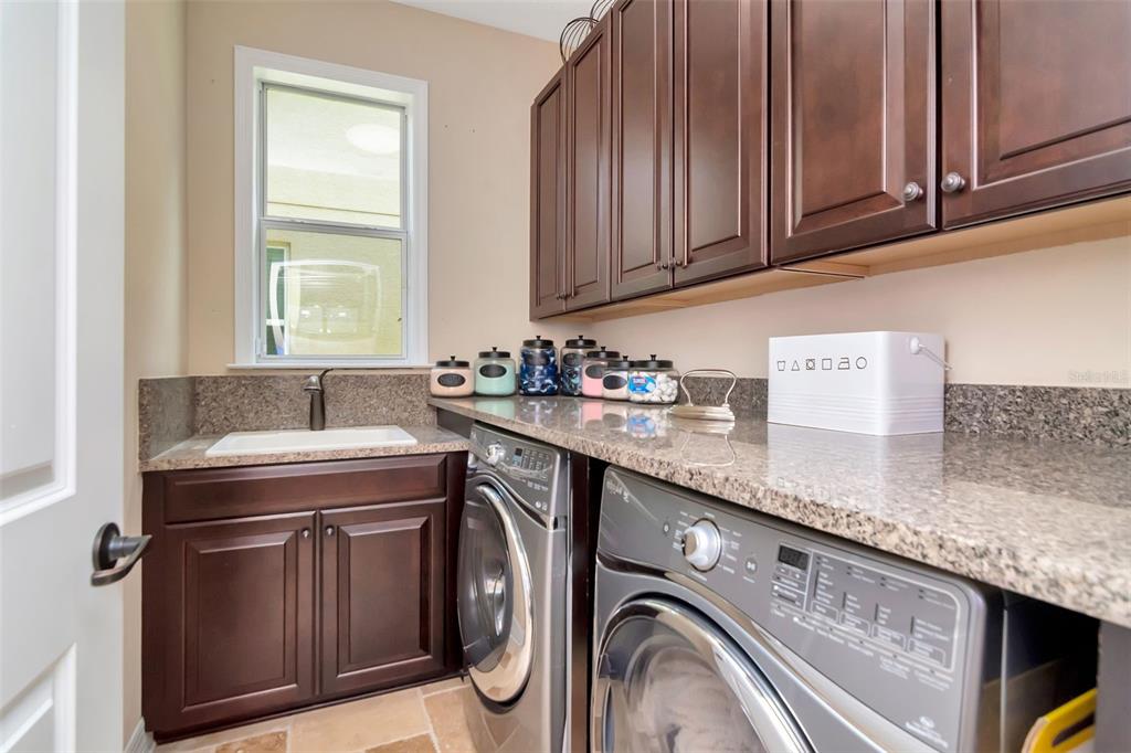 4527 Scarlet Loop Wesley Chapel, FL 33544 - Photo 17 of 33 a utility room with granite countertop cabinets washer and dryer
