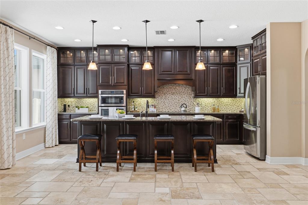 4527 Scarlet Loop Wesley Chapel, FL 33544 - Photo 9 of 33 a kitchen with granite countertop a refrigerator and wooden cabinets